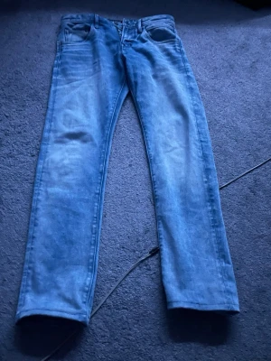 Ljusblå raka jeans - Säljer ett par ljusblå jeans med rak passform och klassisk femficksdesign. Jeansen har normal midja och är tillverkade i denim. Perfekta för en avslappnad och stilren look.