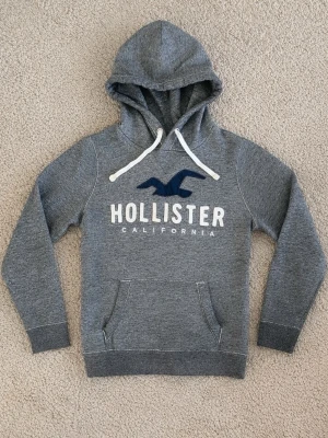 Hollister Hoodie - Snygg grå Vintage hoodie från Hollister. - Tröjan är i fint skick och har används sparsamt. - Storlek: S - Pris: 699kr - Först till Kvarn!!!