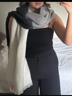 Mjuk halsduk i grå och svart ton - En stor och fluffig halsduk i blockfärger med svart, mörkgrå, ljusgrå och vit. Halsduken har en rektangulär form och är perfekt att svepa flera varv runt halsen. Materialet ser ut att vara borstat och supermjukt, vilket ger en mysig känsla. Kolla min profil för fler plagg! 🥰