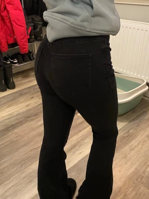 Svarta bootcut jeans Vero Moda - Snygga svarta bootcut jeans från Vero Moda med klassisk femficksmodell och låg midja. Jeansen har en tight passform upptill och utsvängda ben, perfekta till sneakers eller boots. Tillverkade i stretchigt denim för skön känsla.