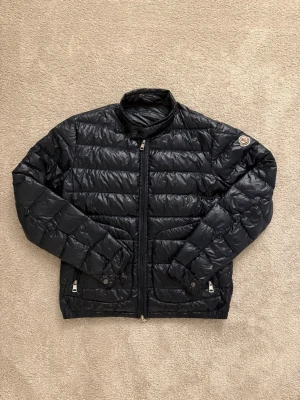 Moncler Acorus - Moncler jacka i modellen ”Acorus”. Jackan är navy blue i storlek 1, vilket motsvarar S. Jackan är sparsamt använd och i mycket fint skick. Givetvis äkta, inhandlad på haiendo. Tveka inte att höra av dig vid eventuella frågor!