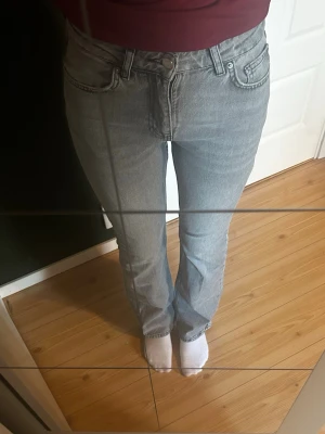 Ljusgråa - Säljer ett par gråa jeans med bootcut passform och klassisk femficksdesign. Jeansen har normal midja och stängs med knapp och dragkedja. Perfekta till en avslappnad stil och passar till det mesta i garderoben. STORLEK: 36. Innerbenalängd: 80cm, Midjemått rakt över: 37cm