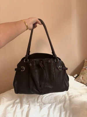 Mörkbrun läderhandväska salvatore ferragamo - Jättesnygg mörkbrun väska som får plats med allllt. Från salvatore ferragamo perfekt skick