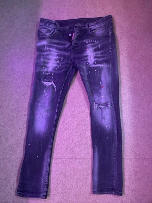 Dsquared2 jeans grå slim  - Säljer ett par grå DSQUARED2 slim jeans med slitningar och hål på knäna samt färgstänk för en cool, trendig look. Ganska bra skick. Jeansen har fem fickor och dragkedja med knapp. Storlek 46 ungefär 180 cm passar de för. Perfekta för dig som gillar streetstyle. Pris kan diskuteras.