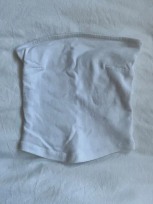 Vit bandou top i bomull - En enkel och stilren vit bandou top i mjukt bomullstyg. Modellen är rak och utan mönster, perfekt för en clean look. Passar till många olika outfits. 