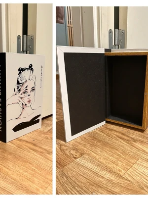  förvaringsbox bokdesign - Snygg förvaringsbox utformad som en bok med illustration av en tjej med uppsatt hår och solglasögon. Omslaget är vitt och svart med texten 'Always Fashion'. Insidan är svart och ramen har trälook. Perfekt för att gömma småsaker på ett stilrent sätt.