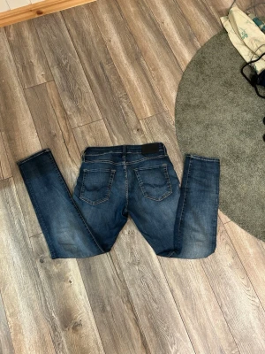 Mörkblå slim fit jeans - Säljer ett par mörkblå slim fit jeans med klassisk femficksdesign och snygga slitningar. Jeansen har kontrastsömmar och normal midja. Perfekta för dig som gillar en smalare passform och tidlös stil. Storlek 30/30.