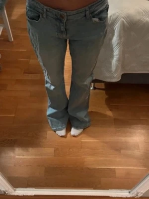 Ljusblå bootcut jeans - Säljer ett par ljusblå bootcut jeans med klassisk femficksdesign och låg midja. Jeansen har en avslappnad passform och är tillverkade i denim. Perfekta för en trendig och avslappnad stil.