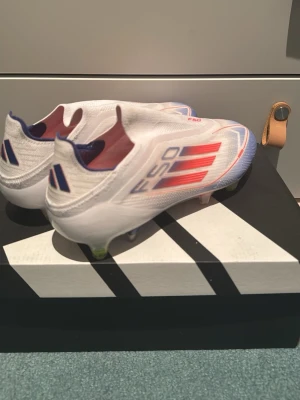 Adidas F50 fotbollsskor i vitt och blått - Hej. För ett halvår sen fick jag dessa sprillans nya f50 speed, men tyvärr blev jag skadad. Jag har därför inte kunnat använda skorna då de är helt nya. På köpet får du även med ståldobbar att byta till. Detta är ett par riktigt bra och fina skor, hoppas du gillar de! Nypris = 2498