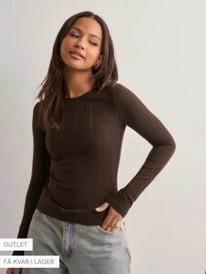 Brun ribbad långärmad topp med öppen rygg - Snygg brun långärmad topp med ribbad struktur och cool öppen rygg med snörning. Perfekt för dig som vill ha en trendig och unik look. Passar till jeans eller kjol och är riktigt bekväm tack vare det mjuka materialet.