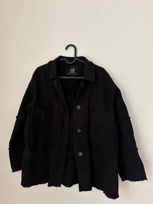 Svart jacka från Zara - Cool svart jacka från Zara med råa kanter och stora fickor framtill. Jackan har knappar hela vägen och en avslappnad, oversized passform. 