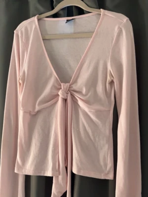 Ljusrosa omlottopp med knyt - Supersöt ljusrosa omlottopp med långa ärmar och knyt framtill. Toppen har en djup v-ringning och är gjord i mjukt bomullsmaterial. Perfekt att styla med jeans eller kjol för en trendig look. Denna är från Gina tricot och säljer pga att jag inte använder 💞