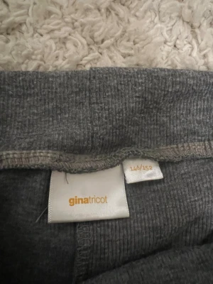 Grå bootcut leggings från Gina Tricot - Mörkgrå leggings från Gina Tricot med bootcut-ben och bred, vikt linning. Mjukt och stretchigt material som sitter skönt. Perfekta för en avslappnad och trendig look.