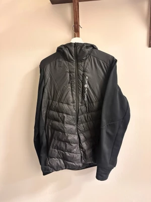 Svart pufferjacka från Sailracing - Svart pufferjacka från Sailracing med quiltad front och rygg, samt släta svarta ärmar. Storlek M