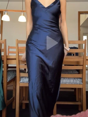 Mörkblå balklänning i satin - Otroligt vacker mörkblå långklänning med v-ringning och smala axelband. Klänningen har en elegant, figurnära passform och är tillverkad i glansigt satinmaterial som ger en lyxig känsla. Perfekt för balen. Priset är högre på grund av tull och frakt den var från USA, så man tjänar fortfarande på det då den kostnaden var så pass dyr!
