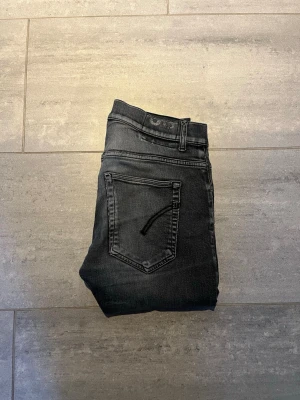 Dondup jeans - Säljer ett par svarta skinny jeans med diskreta slitningar och tvättade detaljer. Jeansen har klassisk femficksdesign, normal midja och smal passform hela vägen ner. Perfekta för en avslappnad och trendig look.