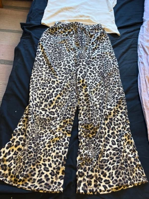 Leopardmönstrade loungebyxor - Säljer ett par mjuka och sköna loungebyxor med leopardmönster i beige, brunt och svart. Byxorna har resår i midjan och vida ben för extra komfort. Perfekta för chill dagar hemma eller när du vill ha en avslappnad stil.