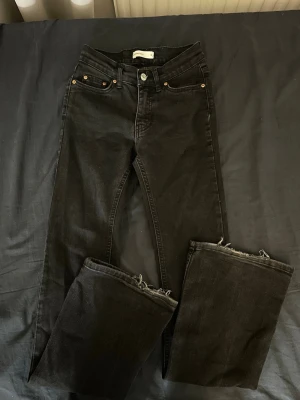 Svarta raka jeans med råa kanter - Snygga svarta jeans med rak passform och råa, fransiga benslut. Klassisk femficksmodell med knapp och dragkedja framtill. Perfekta för en avslappnad och trendig look.