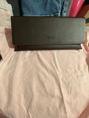 Fendi solglasögon med gulddetaljer - Snygga solglasögon från Fendi med svarta glas och guldfärgade detaljer på bågarna. Kommer i ett elegant svart fodral med Fendi-logga. Perfekt accessoar för att lyfta din stil med en lyxig touch. //obs jag har Ingen kvitto