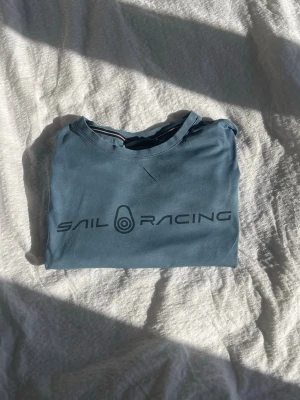 Blå Sail Racing t-shirt - Snygg blå t-shirt från Sail Racing med tryckt logga framtill. 