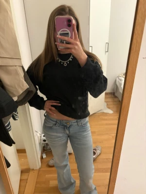 Svart cropped tjocktröja från H&M Divided - Svart cropped tjocktröja från H&M Divided i mjukt material. Klassisk modell med ribbade muddar vid ärmslut och nederkant. Perfekt till jeans eller leggings för en chill och trendig look.