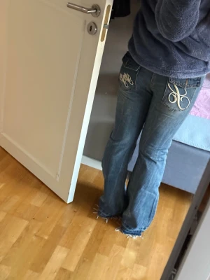 Blå bootcut jeans  - Säljer ett par blå bootcut jeans med klassisk femficksmodell och broderade detaljer på bakfickorna. Jeansen har en lätt tvättad look och är tillverkade i denim med skön passform. Perfekta för en avslappnad och trendig stil. Har bara testat på men aldrig använt dem då de är lite för tighta för mig.