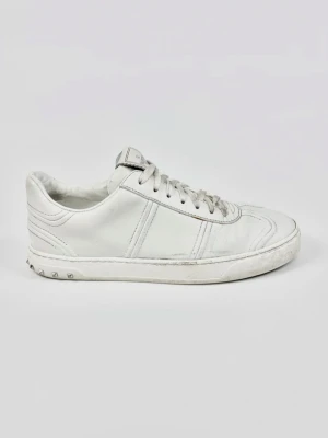 Vita sneakers från Valentino Garavani - Stilrena vita sneakers från Valentino Garavani i läder med klassisk låg silhuett. Skorna har vita snören, diskreta sömdetaljer och små nitar på hälen för en edgy touch. Perfekta för dig som gillar minimalistisk och exklusiv streetstyle.