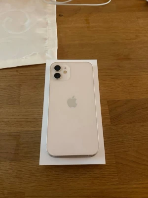 Vit iPhone 12 med dubbla kameror - Säljer min iPhone 12 då jag köpt en ny. Allt fungerar som det ska – kamera, Face ID, högtalare och knappar. Telefonen är återställd och redo för ny användare. Har ett skyddande plats på så det finns inga skador på skärmen utan endast på plastet!