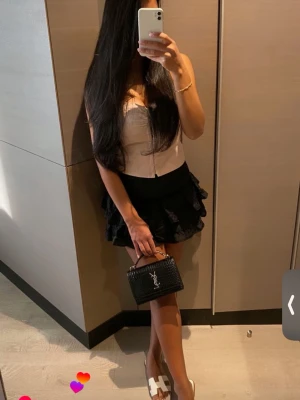 Svart volangkjol med spetsdetaljer - Supersöt svart kortkjol med flera lager volanger och fina spetsdetaljer. Kjolen har en bred midja och är perfekt för dig som gillar en feminin och trendig stil. Passar till både sneakers och boots.