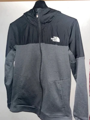 Svart och grå vindjacka från The North Face - Snygg svart och grå vindjacka från The North Face, helt ny skick samt knappt använd, perfekt för våren!