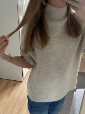 Beige stickad tröja  - Säljer en beige stickad tröja med korta ärmar och hög krage. Köpt från gina tricot i storlek xs. Använd fåtal gånger o är i mycket bra skick.❤️