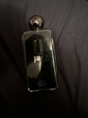 Armaf Club de Nuit PM parfym - Snygg parfymflaska från Armaf, Club de Nuit PM. Flaskan är svart med spegelblank finish och har en rund, metallisk kork. Modern och stilren design som sticker ut i parfymhyllan. Perfekt för dig som gillar exklusiva dofter och elegant look.