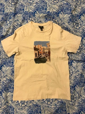 T-shirt - Säljer en cremevit t-shirt från H&M i regular fit storlek S med ett snyggt italienskt tryck. Jättefint skick, skriv gärna vid frågor eller funderingar!