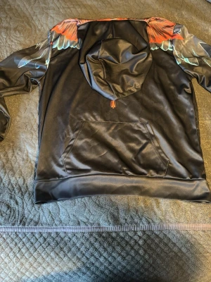 Svart hoodie med färgglad fågeltryck - Jätte snygg hoddie, den va lite för stor för mig därför jag vill sälja den. Storlek L