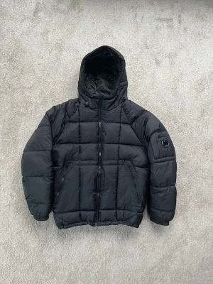Svart pufferjacka från C.P. Company - Säljer en svart vårjacka från C.P. Company! Passar perfekt till den kommande våren! Inte särskilt använd och är i mycket gott skick! Hör av dig vid minsta fråga!
