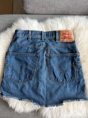 Blå jeanskjol från Levi's - •Ett par Levi's 550 Relaxed Fit jeansshorts i blå denim.  •Shortsen har en dragkedja framtill och klassiska fickor både fram och bak.  •Midjan är designad för en avslappnad passform. •Perfekt för en avslappnad och trendig look. •Mycket fint skick. Tvättad  🚭Djurfritt och rökfritt hem 🌸Se gärna mina andra annonser för samfrakt ✨Har bundle-rabatt