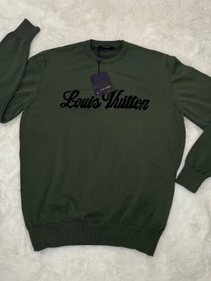 Grön Louis Vuitton tröja - Snygg grön tröja från Louis Vuitton med svart broderad logga på bröstet. 