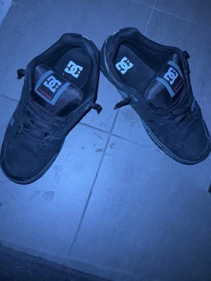 Svarta DC sneakers med läderdetaljer - Säljer ett par grymma DC Shoes som är vattenresistenta. Skorna köptes den 11 januari, men säljes nu då de tyvärr inte passade mig. De är helt oanvända och i nyskick. Detta är en väldigt bekväm modell med bra dämpning och stöd, vilket gör dem perfekta att gå i hela dagen. Tack vare att de är vattenresistenta fungerar de lika bra på stan som i lite tuffare väder. • Egenskaper: Mycket bekväma, rejäl sula och vattenavvisande material. • Inköpsdatum: 11 januari. • Kvitto och kartong medföljer 