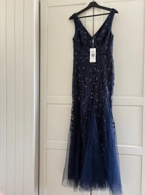 Mörkblå långklänning Ever Pretty - Elegant mörkblå långklänning från Ever Pretty med v-ringning och broderade paljettmönster i bladmönster. Klänningen har en figurnära passform upptill och utsvängd kjol i tyll. Perfekt för speciella tillfällen och ger en lyxig känsla. Prislappen kvar och pris går att diskuteras!!💓