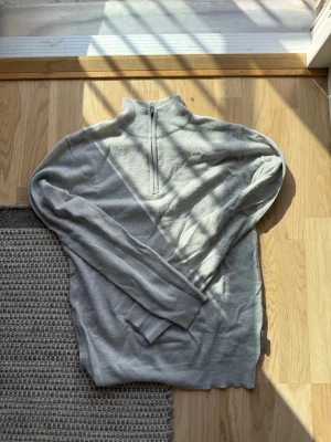 Ljusgrå halvzip-tröja French Connection - Ljusgrå quarter zip i storlek XS. Tillverkad i mjukt material och har ribbade muddar vid ärmslut och nederkant. Perfekt för lager på lager och enkel att matcha med olika outfits.