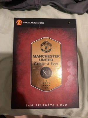 Manchester United Greatest Ever DVD-box - Samlarutgåva med 4 DVD-skivor om Manchester Uniteds bästa spelare genom tiderna. Boxen är röd och svart med gulddetaljer och innehåller skivor om mittfältare, målvakter & försvarare, anfallare samt resultat. Perfekt för fans av fotboll och klubben.