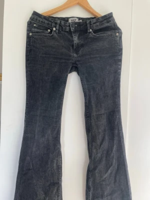 Svarta bootcut jeans från 157 - Snygga svarta bootcut jeans från 157 med klassisk femficksdesign och lätt tvättad look. Jeansen har normal midja och utsvängda ben, perfekta för en trendig och avslappnad stil. Materialet är denim med en skön känsla.