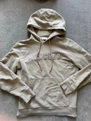 Grön Moncler hoodie med broderad logga - Snygg grön hoodie från Moncler med broderad logotyp på bröstet och klassisk känguruficka. Tröjan har huva med dragsko och ribbade muddar vid ärmslut och nederkant. Perfekt för en chill och stilren look. Daily wear, (nypris 11000kr sök upp om ni vill) (pris kan diskuteras)