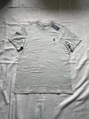 Ralph lauren T-shirt grå strl M - Helt ny Ralph Lauren T-shirt i grå färg säljes. Stilrent och enkelt basplagg med klassisk passform. Perfekt till vardag och sommar. Oanvänd i storlek M snabb frakt 