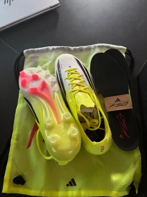 Adidas F50 fotbollsskor gul/svart - Säljer ett par Adidas F50 fotbollsskor i en fräsch gul och svart färg med röda detaljer. Skorna har klassisk låg profil, snörning och lätta material för maximal fart på planen. Medföljer original innersulor och en matchande skopåse.