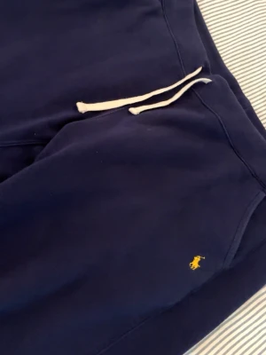 Mörkblå Polo Ralph Lauren Mjukisbyxor - Mörkblå Polo Ralph Lauren mjukisbyxor i riktigt skönt material✨ Riktigt fet passform och sitter sjukt snyggt på kroppen. Perfekta både till chill outfits och mer stilrena fits, samtidigt som de är enkla att matcha. Storlek XL, något stora i midjan men finns snören så de sitter bra ändå 🔥  Vid intresse är det bara att lägga ett bud eller skriva vid minsta fråga eller fundering 💪🏽