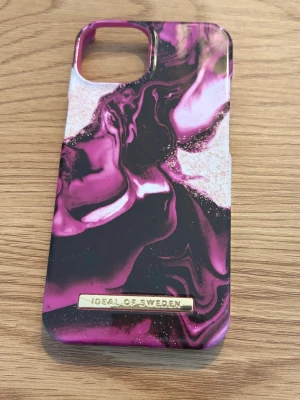 Skalpaket IPhone 13 - Säljer 4 stycken mobilskal till iPhone 13  - Lila/Rosa mönster från Ideal Of Sweden  - Svart plånboks skal från HoldIt - Transparent skal med glittrigt mönster från normal  - Transparent enkelt skal från normal