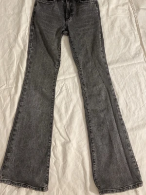 Grå bootcut jeans från Gina Tricot  - Snygga grå bootcut jeans från Gina tricot. Dom har en medel hög midja  Jeansen har blivit lite uttrampade och fått lite slitningar nere vid hälarna som man kan se på bild 4 men annars är dom i bra skick. 