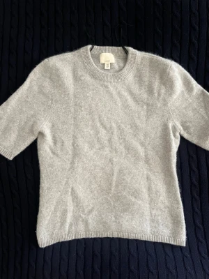 Ljusgrå cashmere-tröja H&M - Kortärmad ljusgrå stickad tröja från H&M i 100% cashmere. Tröjan har korta ärmar, rund halsringning och ribbade kanter. Nästan alldrig använd och köpt för 1000kr