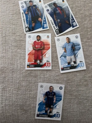 Champions League fotbollssamlarbilder - Fem stycken Champions League samlarkort från Topps med olika fotbollsspelare. Korten har färgstarka bakgrunder i rött, blått och vitt, och visar spelare i matchställ från kända klubbar. Perfekt för dig som gillar fotboll och samlar på sportkort.
